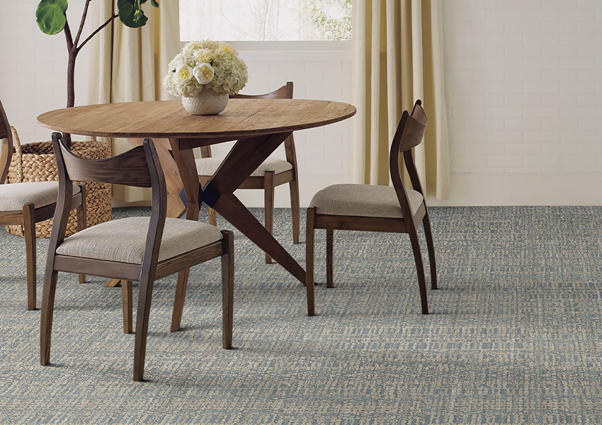 blue and grey pattern carpet in dining room with wood dining set